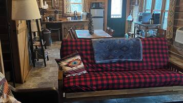 Un acogedor interior de cabaña con sofá, mesa de comedor y zona de cocina.