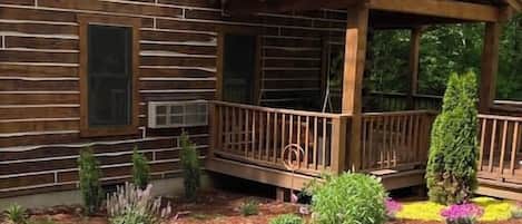 A log cabin with a wooden deck and a covered porch.