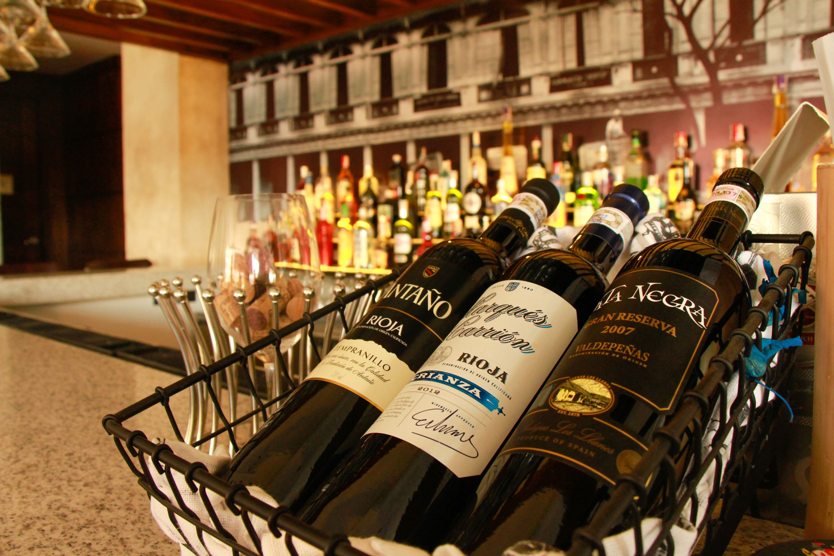 Una estantería para vinos con botellas y copas.