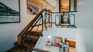 Een meerlaags interieur met houten trappen, een keukenhoek en kunstwerken aan de muren.