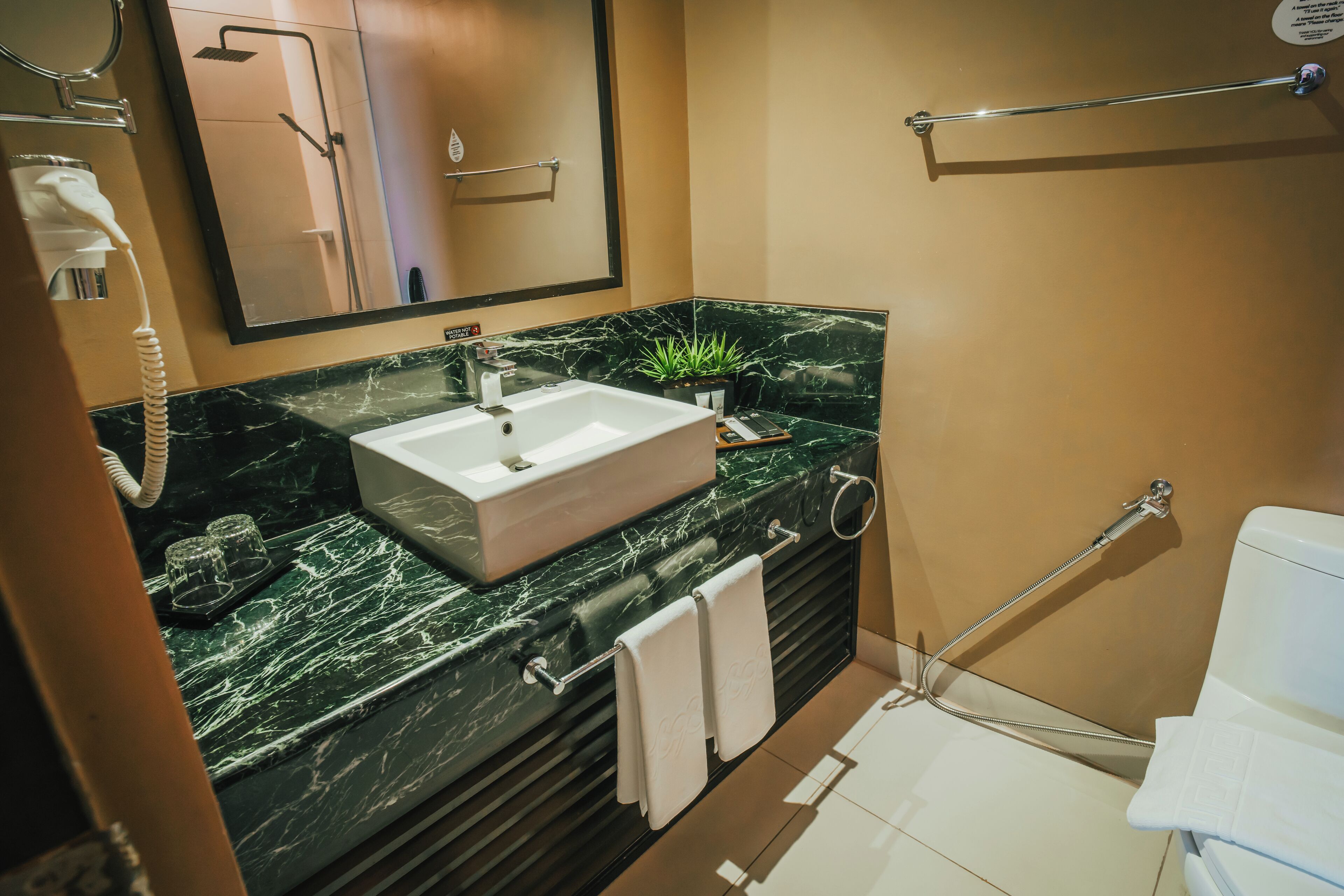 Un baño moderno con lavamanos de mármol, un cabezal de ducha de mano y un inodoro.