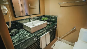 Un baño moderno con lavamanos de mármol, un cabezal de ducha de mano y un inodoro.