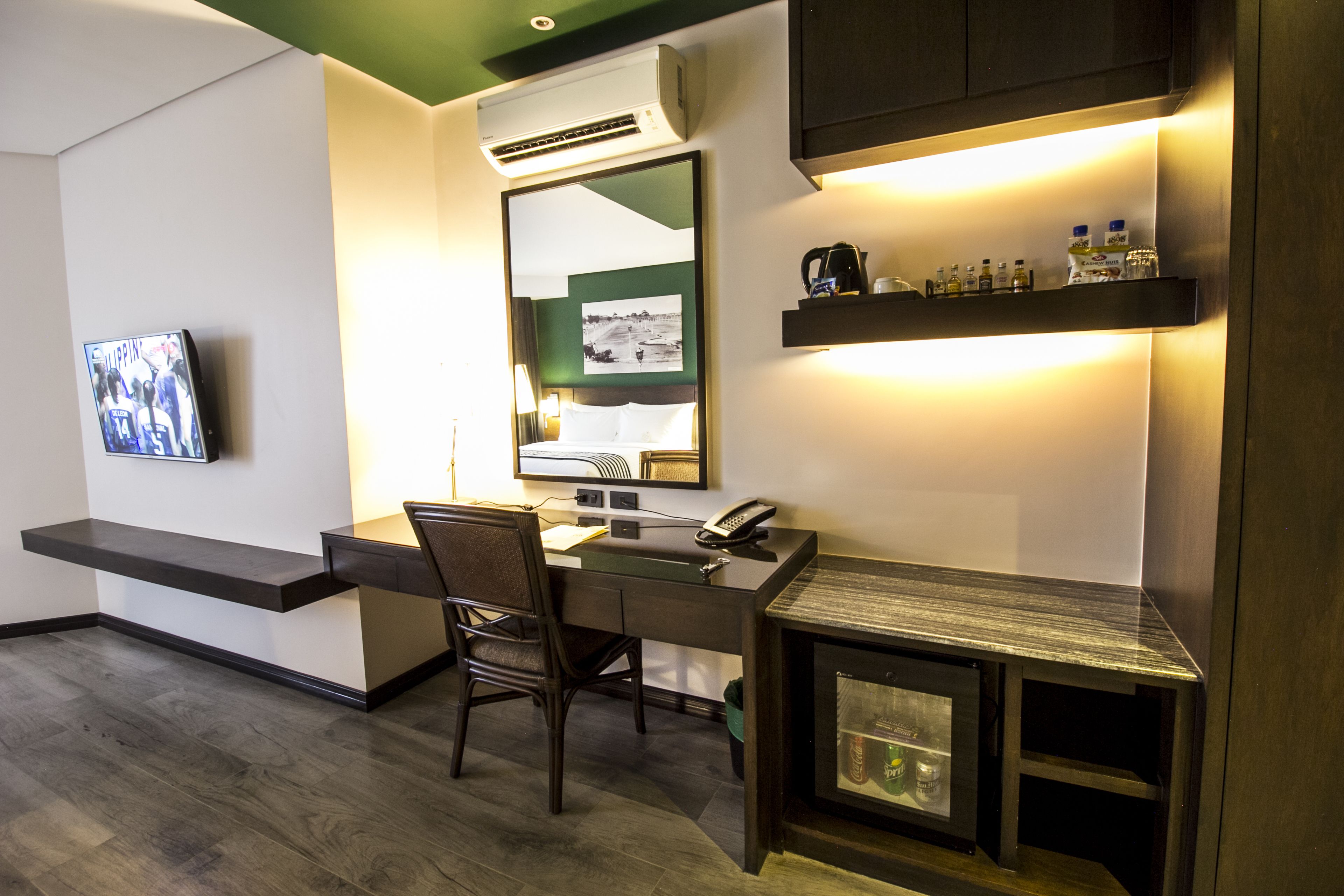 Una habitación de hotel con escritorio, silla y televisor montado en la pared.