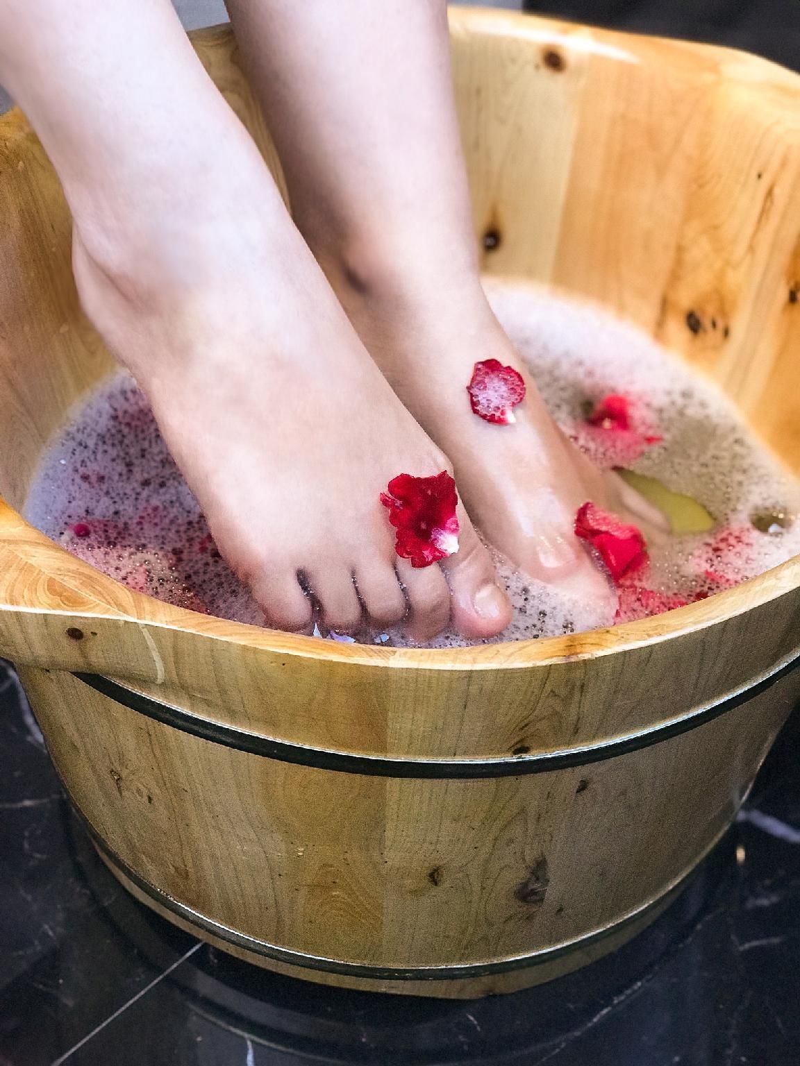 Una tina de madera llena de agua y pétalos de rosa.