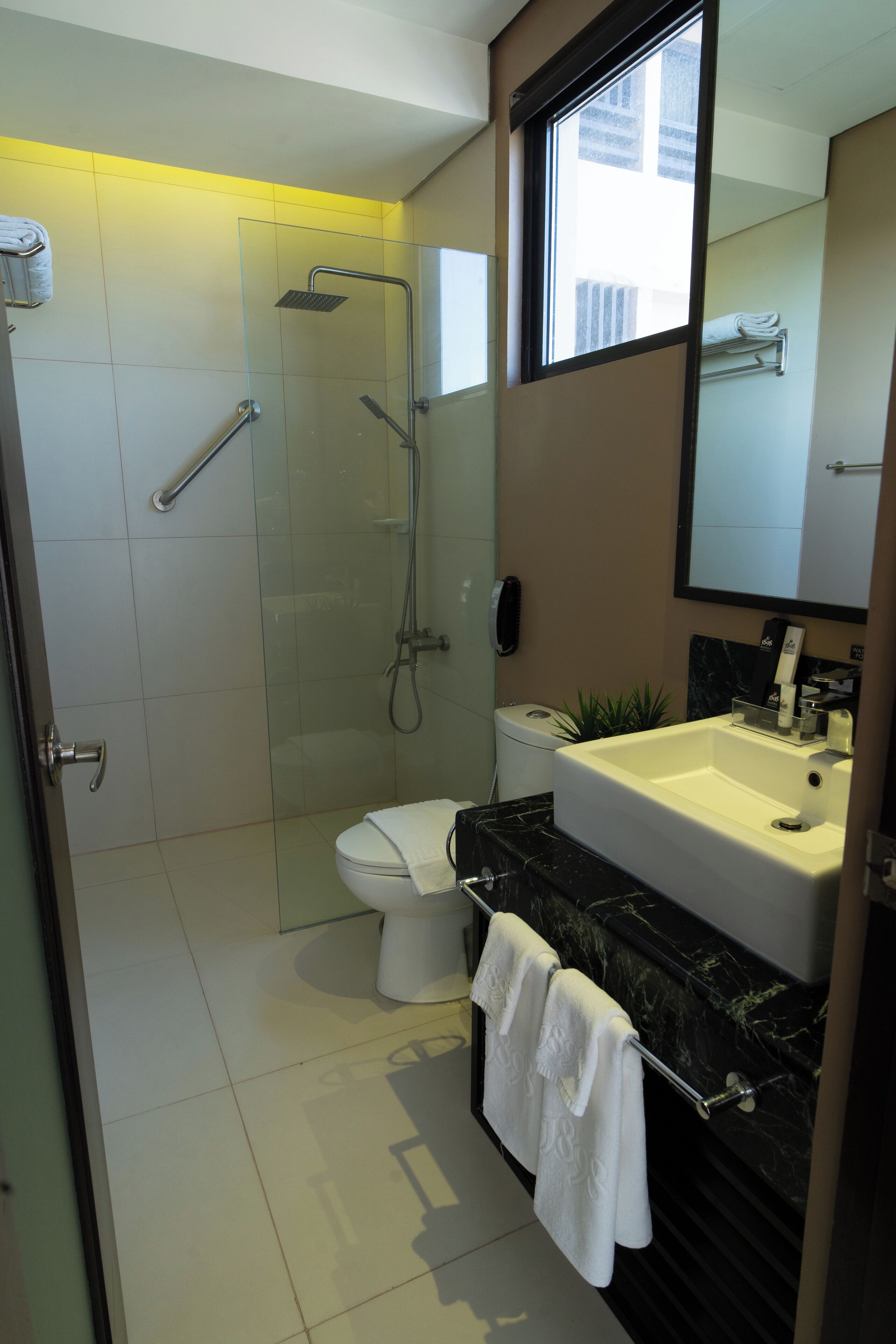 A modern bathroom with a glass shower enclosure, a toilet, a sink with a marble countertop, and a towel rack.