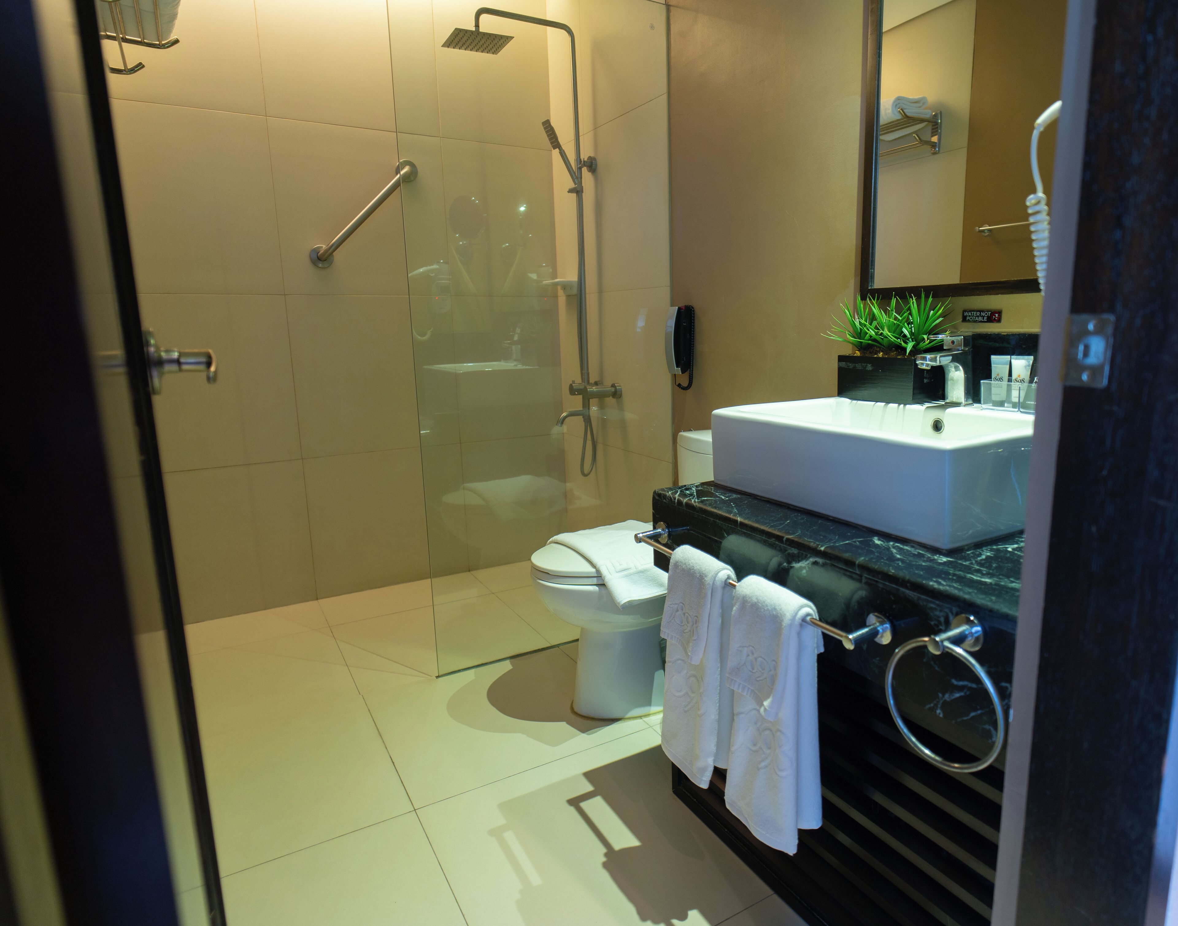Ein modernes Badezimmer mit einer gläsernen Duschkabine, einer weißen Toilette und einem schwarzen Marmorwaschbecken.