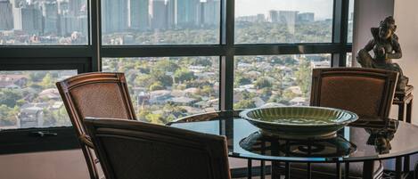 A dining area with a glass table and wicker chairs, a green bowl, and a statue.