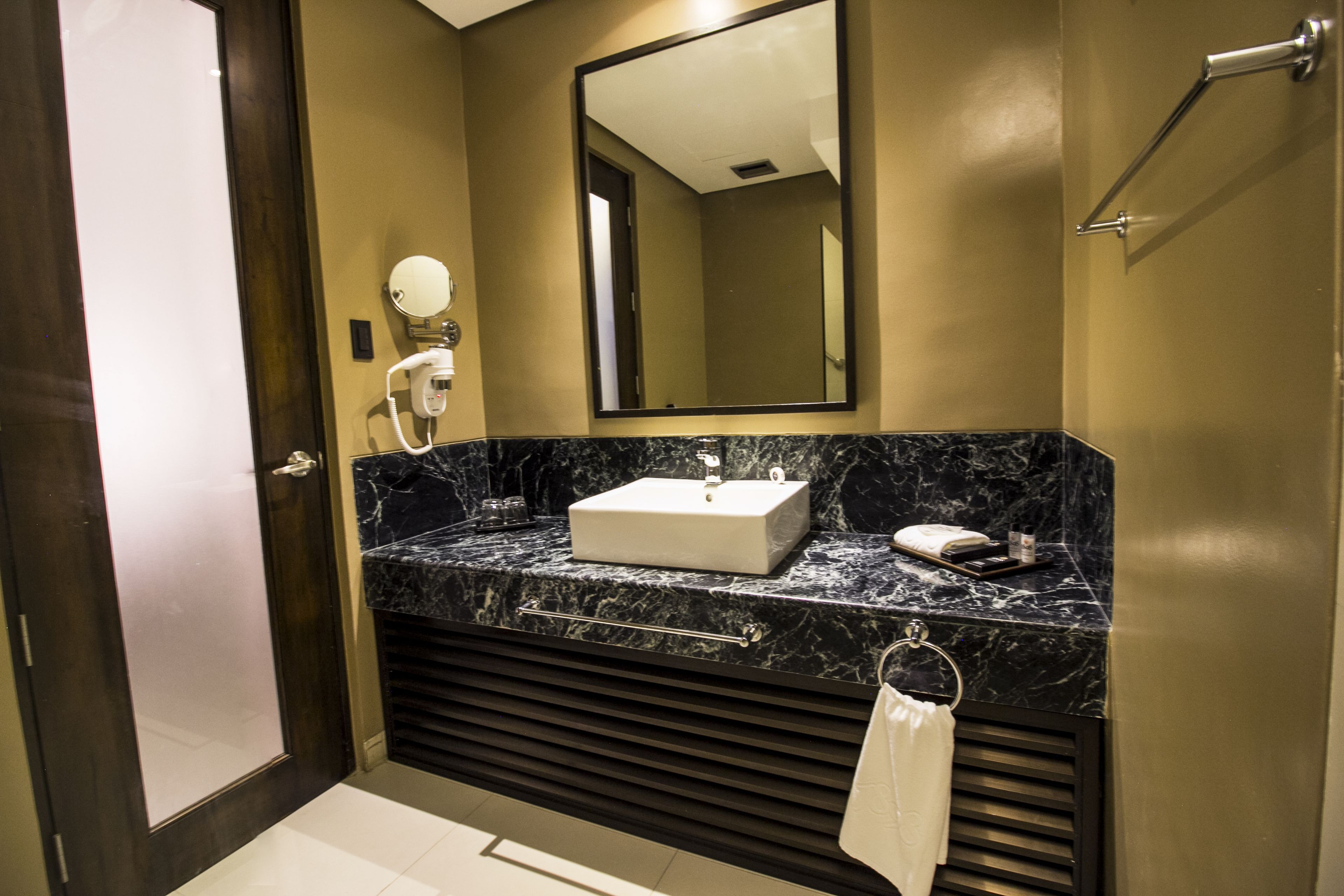 A modern bathroom with a marble sink, a large mirror, and a towel rack.
