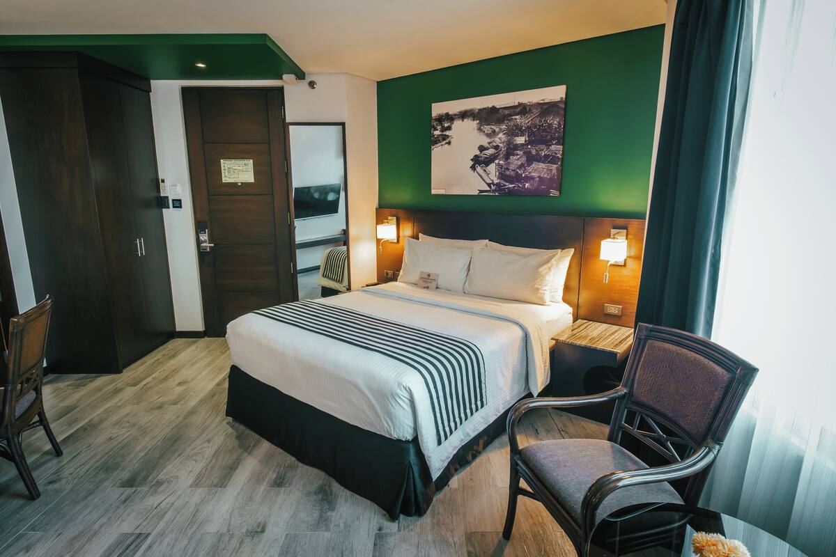Une chambre d’hôtel avec un lit, une chaise, un bureau et une armoire.