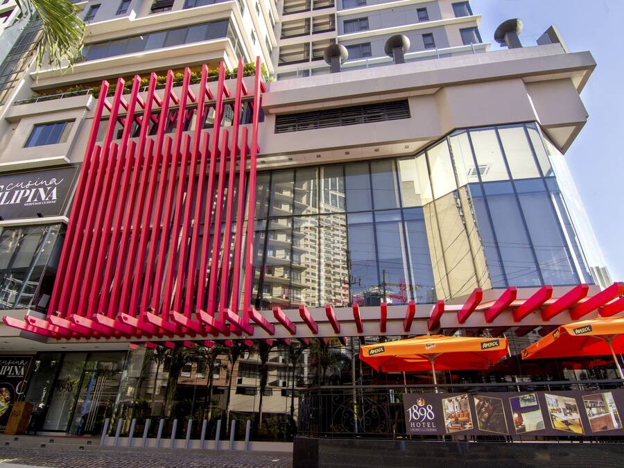 A modern hotel with a prominent red facade and large windows.