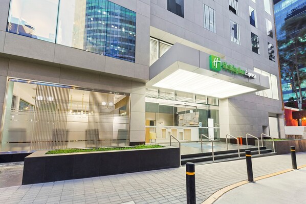 A modern building with a Holiday Inn Express sign, featuring a glass facade, outdoor seating area, and a well-lit entrance. - Holiday Inn Express Lima San Isidro by IHG (Lima)