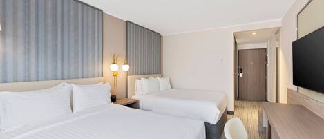 A hotel room with two beds, a desk, a chair, a flat-screen TV, and a large window.