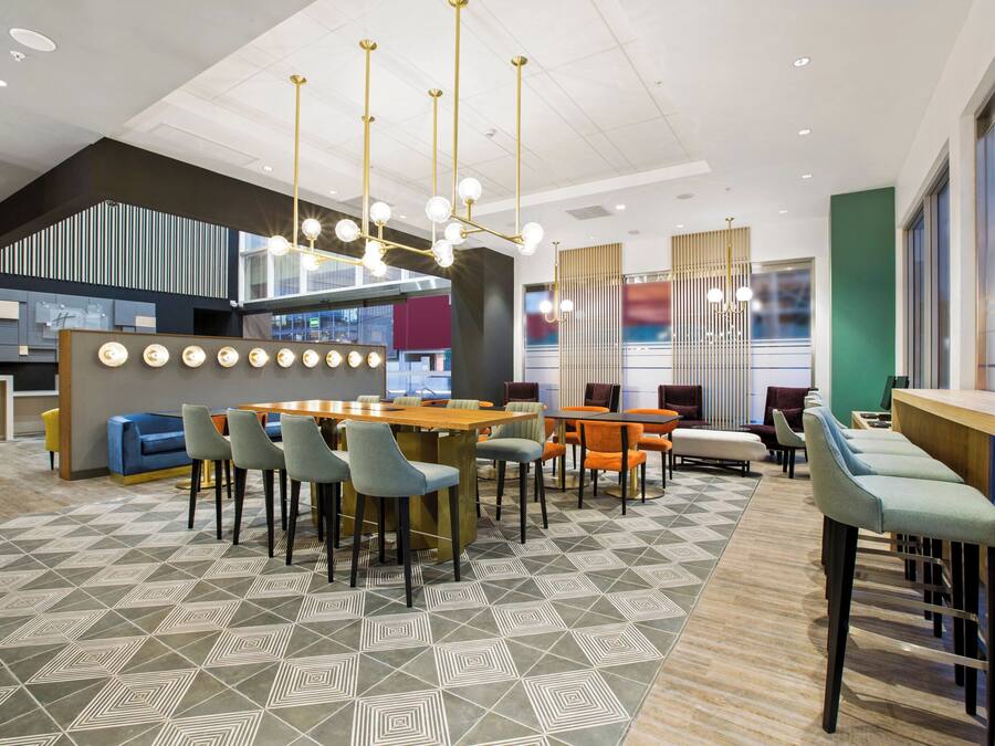 Un interior moderno con una zona de comedor central, asientos de bar y un suelo estampado.