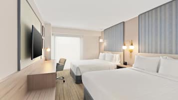 Habitación de hotel con dos camas, un escritorio, una silla, un televisor y un ventanal grande.