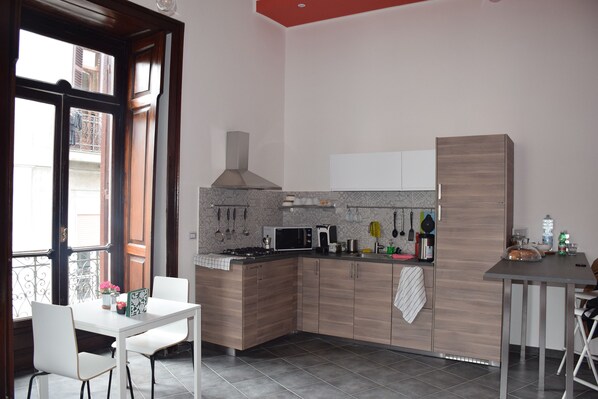 A modern kitchen with a white table and chairs, a microwave, and a stove.