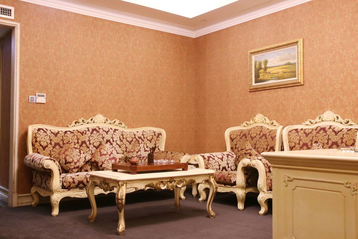 A room with two ornate sofas, a small table with a tray, and a painting on the wall.