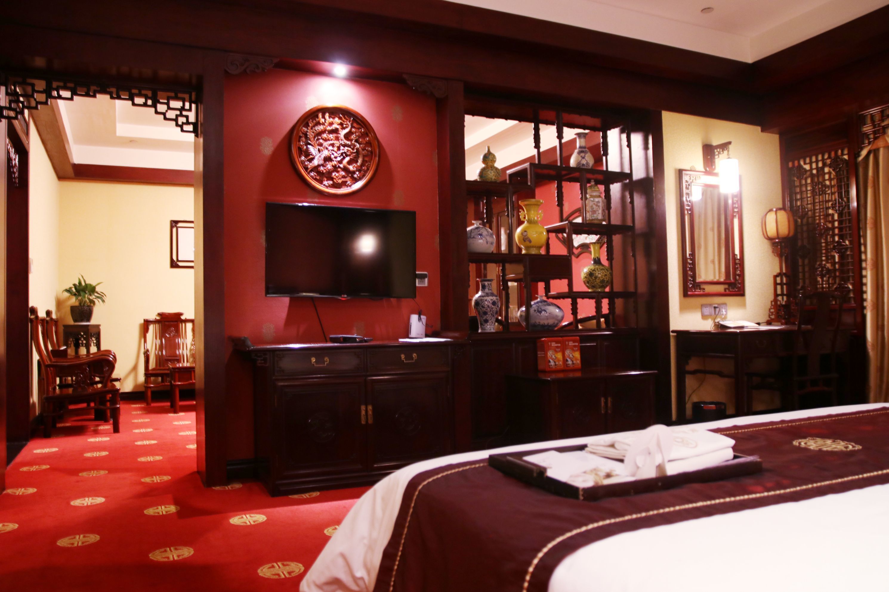 A traditional room with a bed, television, and decorative items.