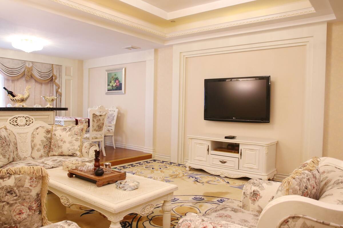 A living room with a sofa, a coffee table, a flat-screen TV, and a decorative cabinet.