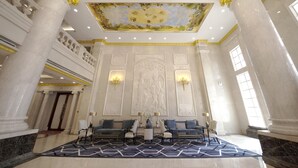 A grand lobby with marble columns, a patterned carpet, and a ceiling mural. - Homeland International Hotel (Huizhou)
