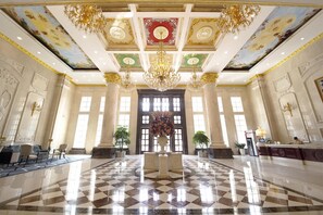 A grand lobby with a checkered floor, ornate chandeliers, and a large floral centerpiece. - Homeland International Hotel (Huizhou)