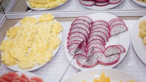 Una presentación de frutas cortadas, entre ellas piña, pitahaya y sandía.