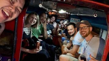 A group of people seated inside a vehicle with a red exterior.