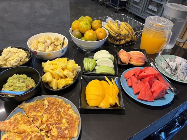 Un bufé de desayuno con diversas frutas, verduras y una tortilla caliente.