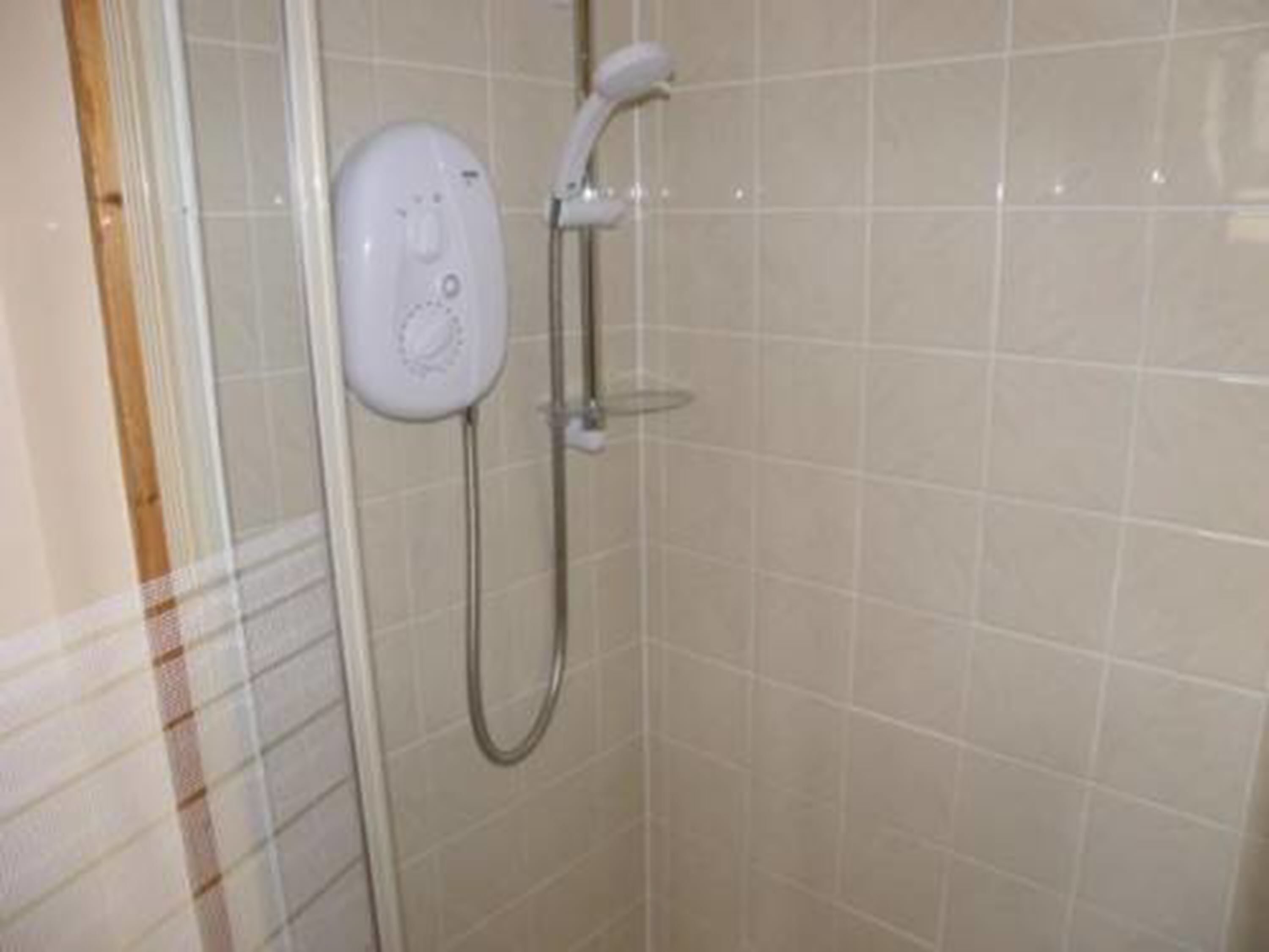 A shower with a handheld showerhead and a wall-mounted control panel.