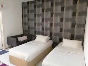 Une chambre d’hôtel avec deux lits, un canapé et une tête de lit à motifs.