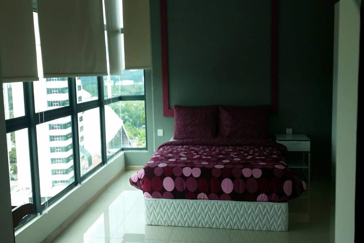A bedroom with a bed, a nightstand, and a window with blinds.