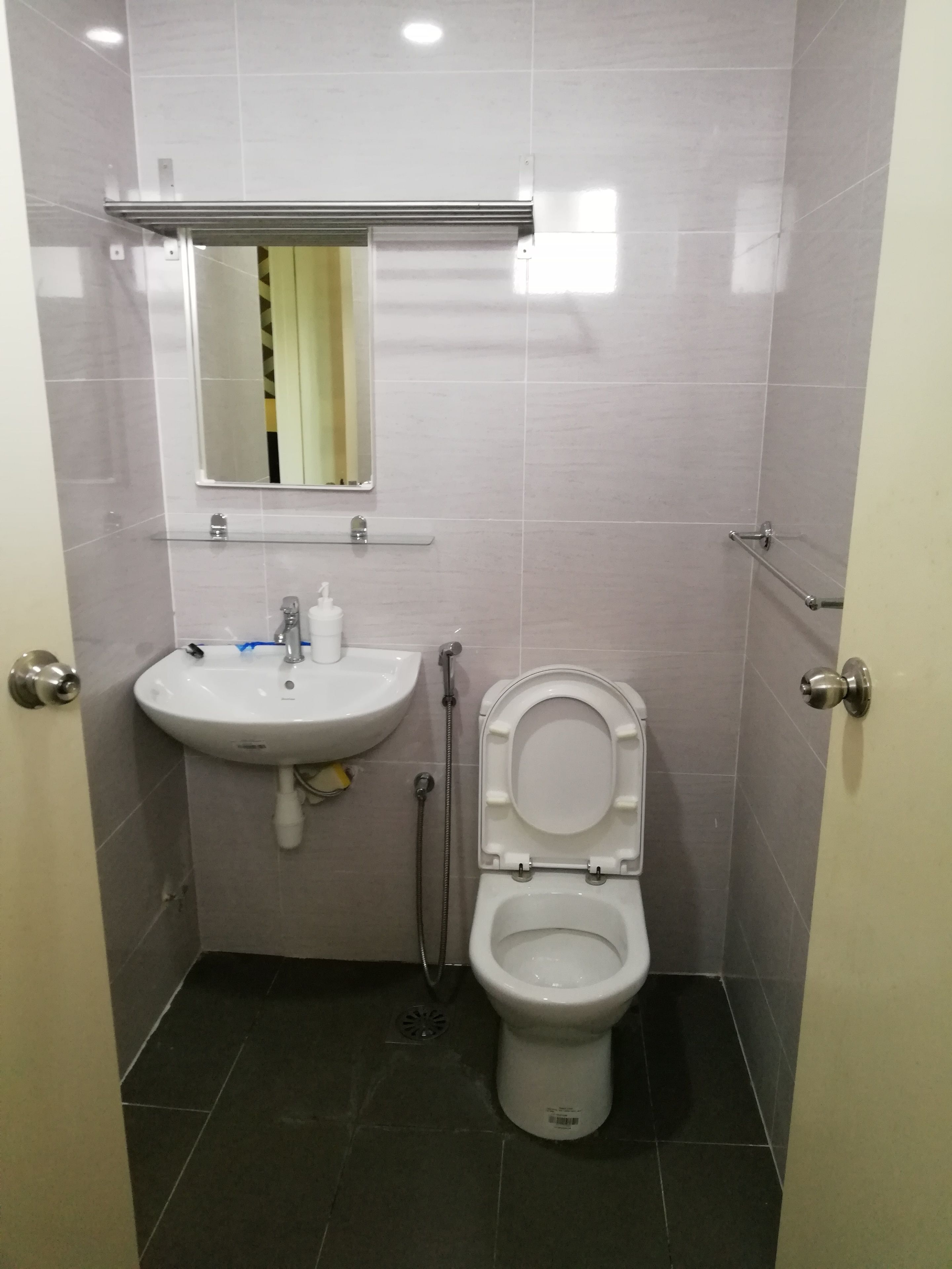 A small bathroom with a white sink, mirror, and toilet.