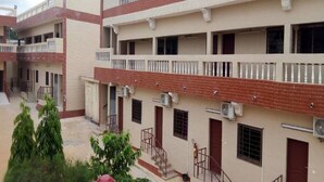 A multi-story building with balconies, air conditioning units, and a gated entrance. - Villa des Hôtes II (Yamoussoukro)