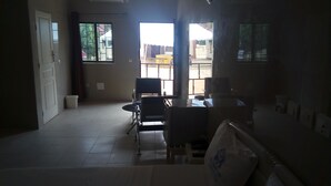 A room with a dining area, a bed, and a view through a window. - Villa des Hôtes II (Yamoussoukro)