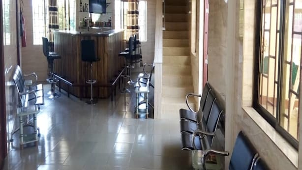 A spacious lobby with a bar area, seating, and a staircase. - Villa des Hôtes II (Yamoussoukro)