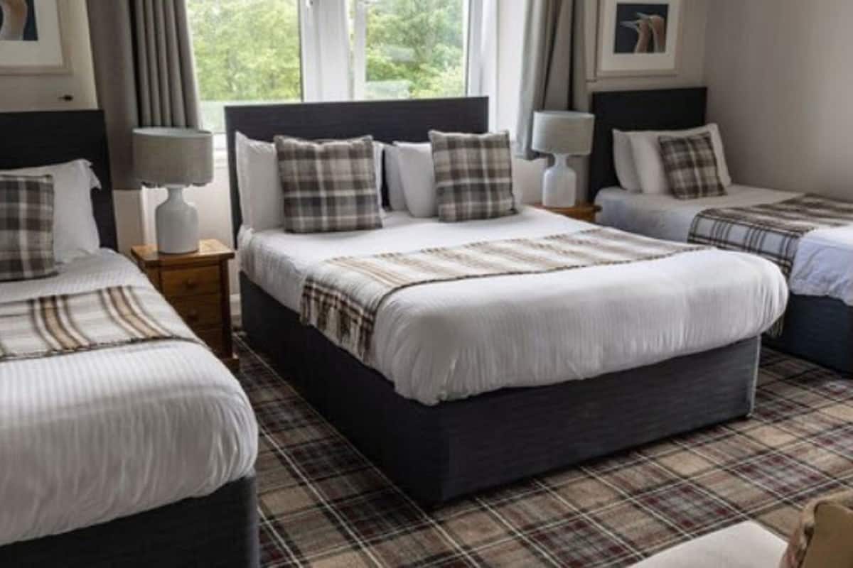 A hotel room with two beds, a large window, and a plaid-patterned floor.