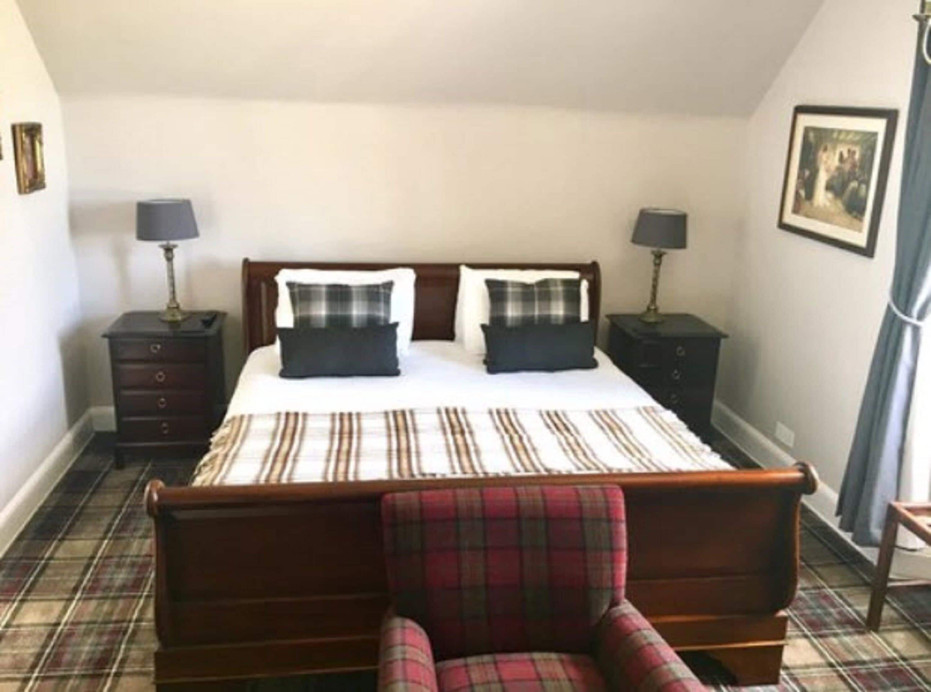 Une chambre à coucher avec un lit, deux tables de chevet, une chaise et un sol à motifs écossais.
