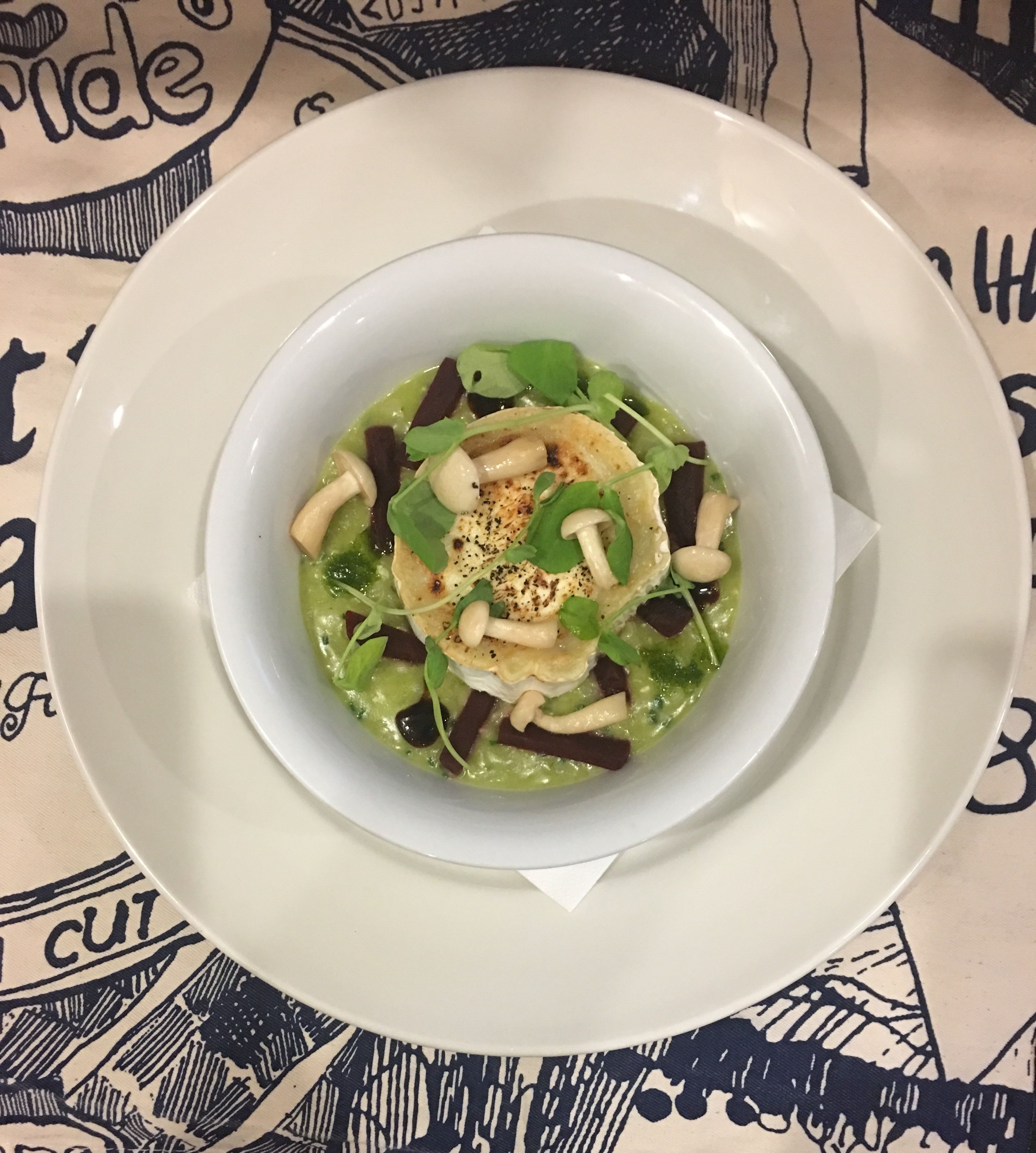 A bowl of salad with various greens and toppings, served on a white plate.