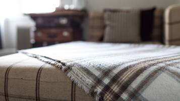A bed with a plaid blanket and a wooden dresser in the background.