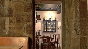 A narrow stone-walled corridor leading to a dining area with wooden furniture and a cabinet with glass doors. - Whitebridge Hotel (Inverness)