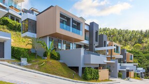 A modern residential complex with multiple levels, balconies, and a hillside location. - Samui Villa Bebe (Koh Samui)