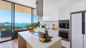 A modern kitchen with a large island, stainless steel appliances, and a view of the ocean. - Samui Villa Bebe (Koh Samui)