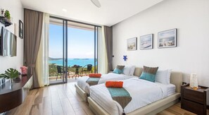 A modern hotel room with a large bed, a balcony with a view of the sea, and a desk with a computer. - Samui Villa Bebe (Koh Samui)