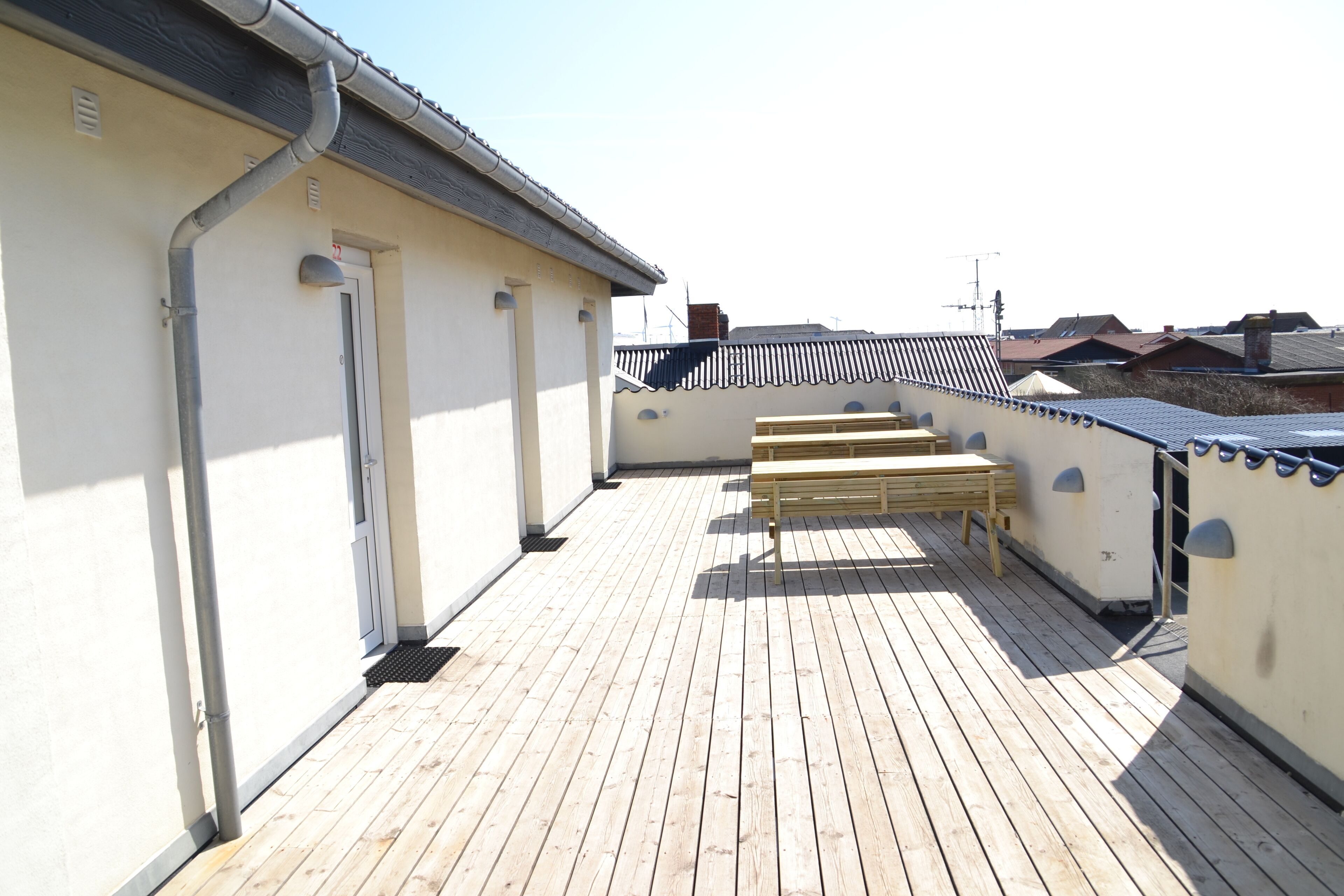 A wooden deck with a bench and a door on a building's side.