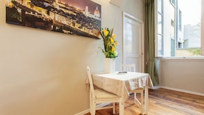 A dining area with a table and chairs, a painting on the wall, and a window with curtains. - Hotel St. James (Florence)
