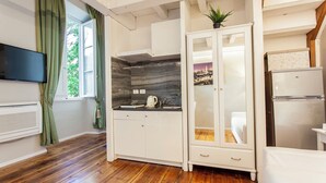 A compact kitchen with a built-in stove, a microwave, and a refrigerator. - Hotel St. James (Florence)