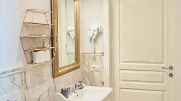 Un bagno con un lavandino bianco, uno specchio con cornice dorata, un porta asciugamani e una porta.