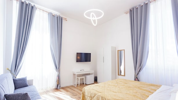 A modern bedroom with a bed, a desk, and a TV. - Hotel St. James (Florence)