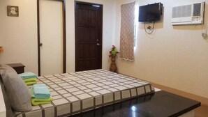 Un dormitorio con cama, televisor montado en la pared y aire acondicionado.