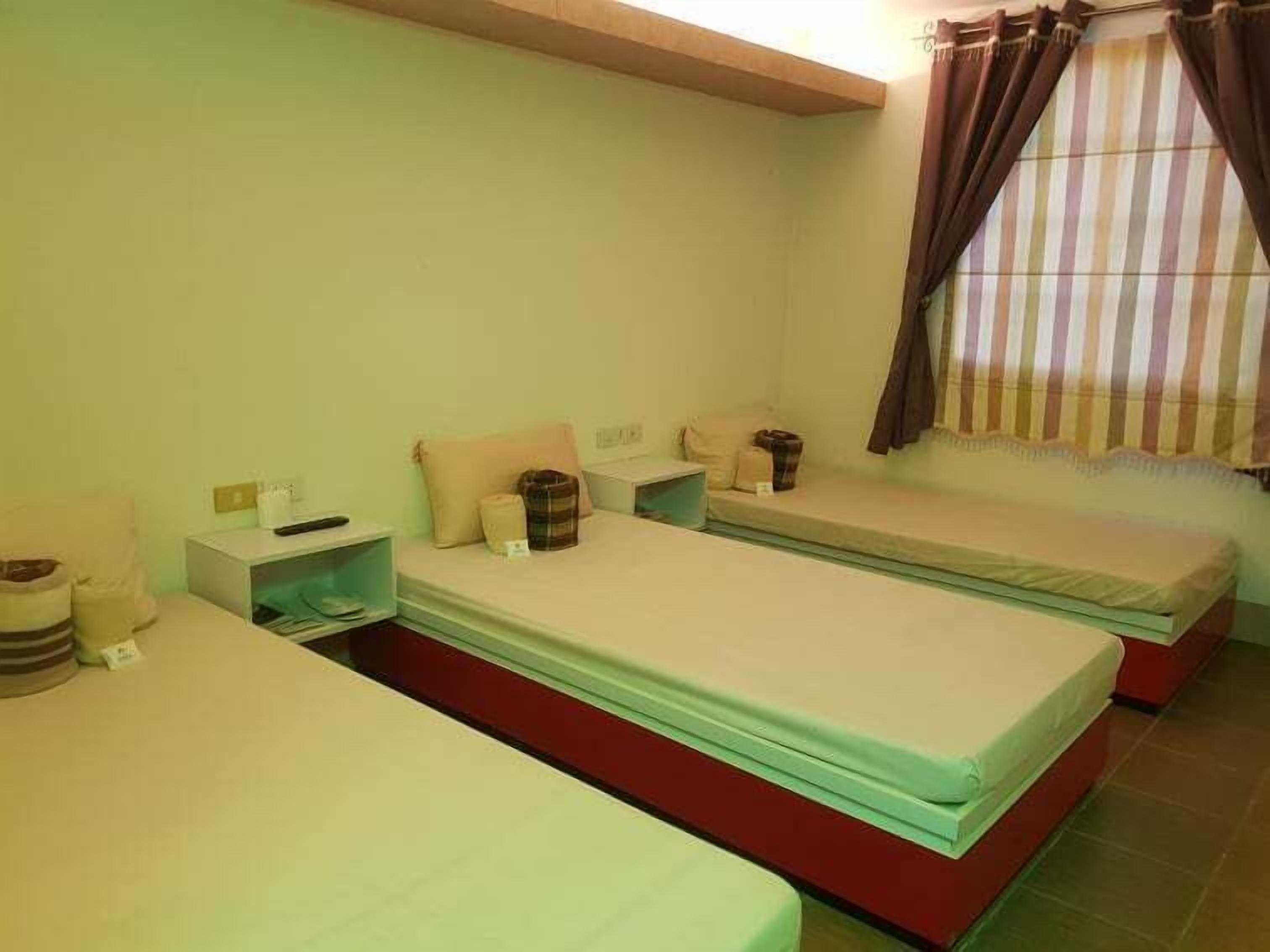 A room with two beds, a small table, and a window with curtains.