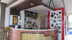 Un área de recepción con mostrador curvo, una pantalla mural y suelo de baldosas.